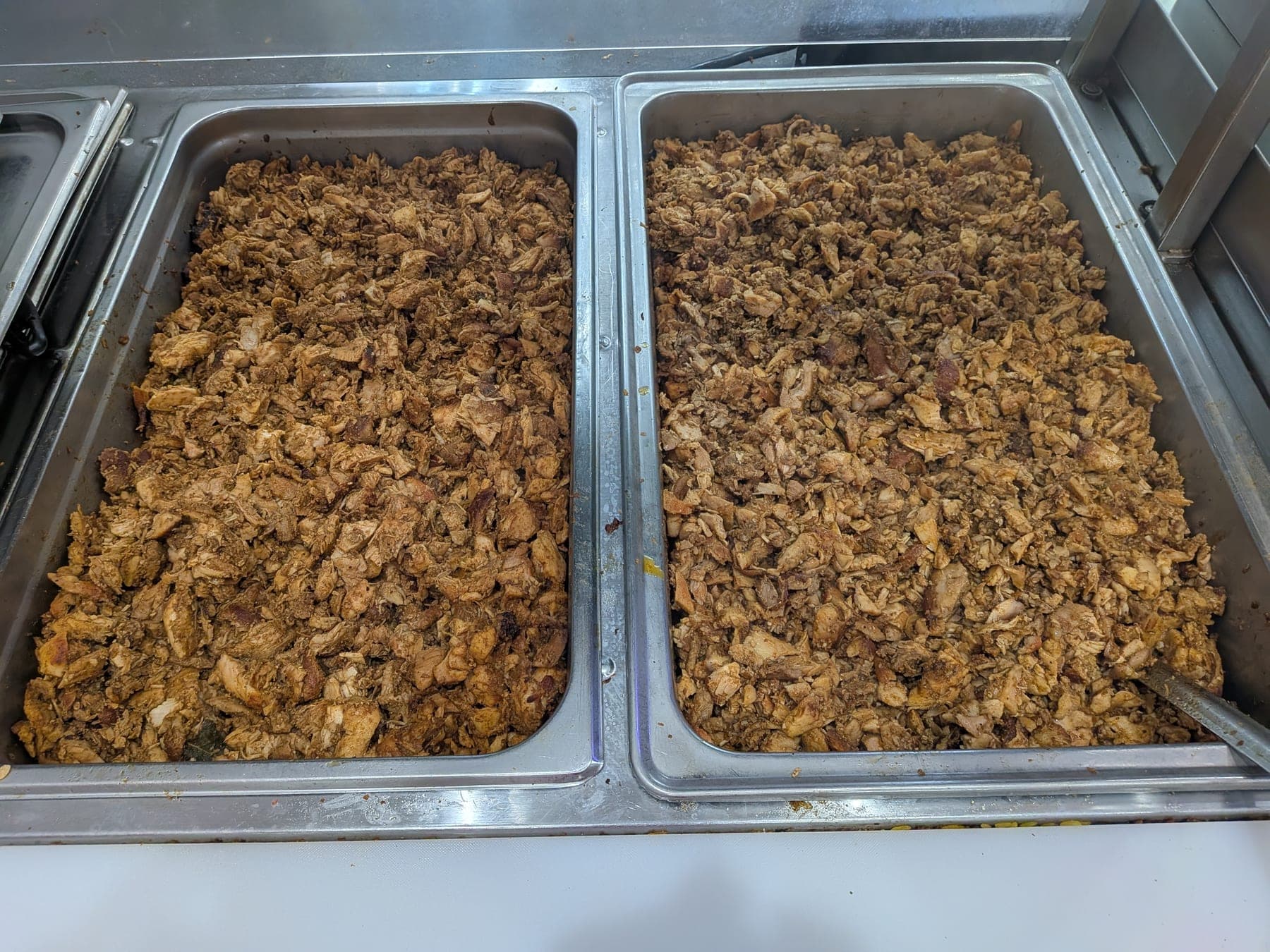 Two full trays of chicken carved off the spit, ready for the line