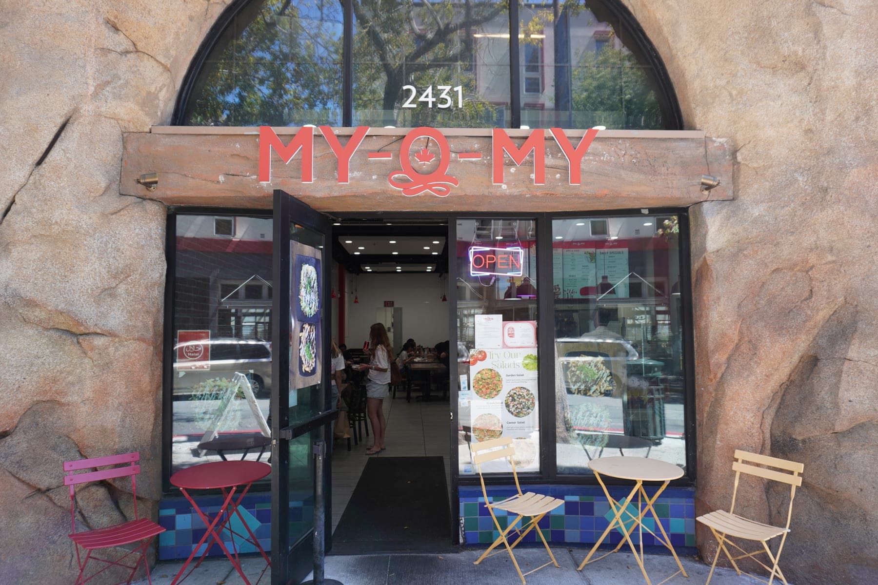 The shopfront at 2431 Telegraph, stone arch, red MY-O-MY sign over the door and bistro tables on the pavement
